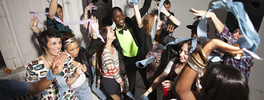 Private party DJ mixing music while guests dance